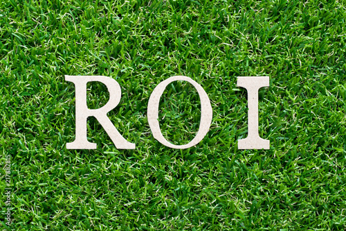 Wood alphabet in word ROI (Abbbreviation of Return on Investment) on artificial green grass background photo