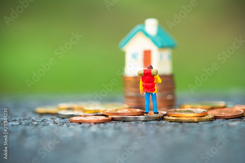 Miniature people  traveler standing on stack coins in front of mini house using as property and financial concept