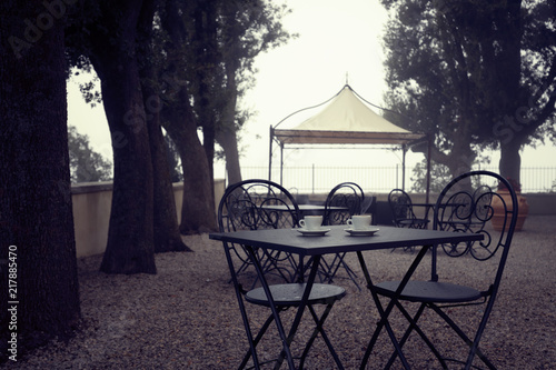 Cups of coffee with smoke at the table in garden. Outdoor cafe terrace