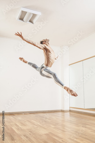 Fototapeta Naklejka Na Ścianę i Meble -  Young beautiful male  ballett dancer jumping in studio