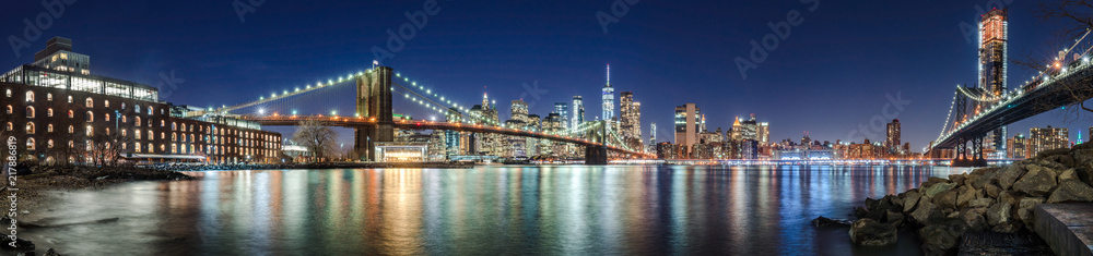 The skyscrapers of Lower Manhattan, the Brooklyn Bridge and the Manhattan Bridge in evening with the East River (panoramic). New York City