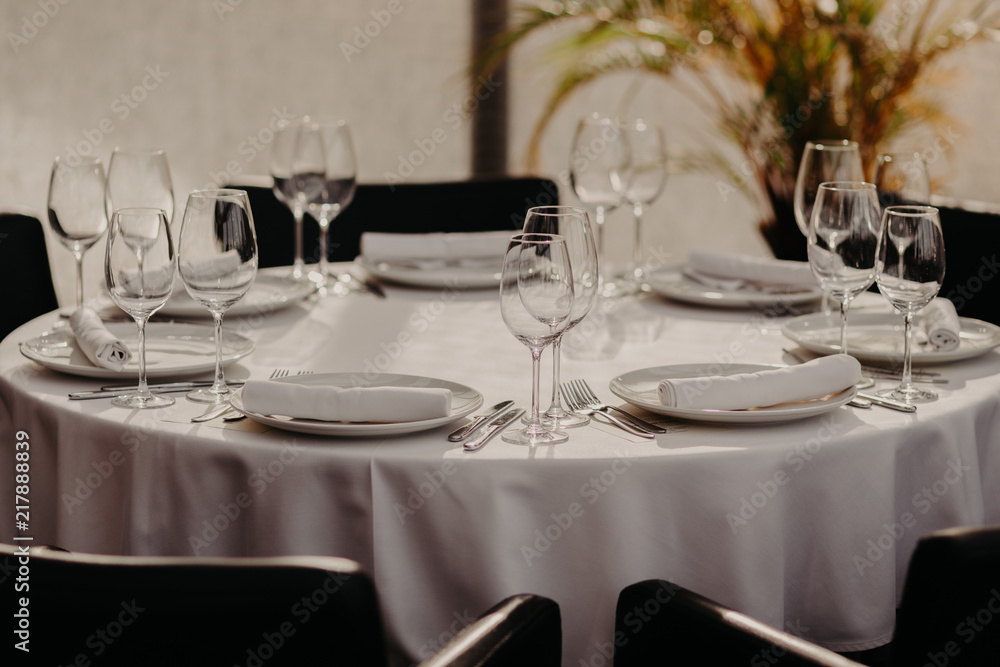 Beautiful decoration of wedding banquet in restaurant with glasses, plates, forks and knives, white tablecloth. Pastel colours. Cozy atmosphere. Celebration concept Beautiful decoration of wedding banquet in restaurant with glasses, plates, forks and knives, white tablecloth. Pastel colours. Cozy atmosphere. Celebration concept