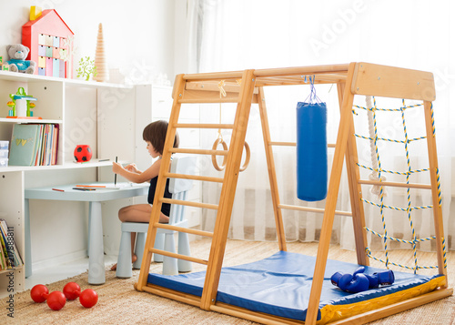 A 3-year-old child paints with pencils sitting at a table in the children's room. Kindergarten, preschooler