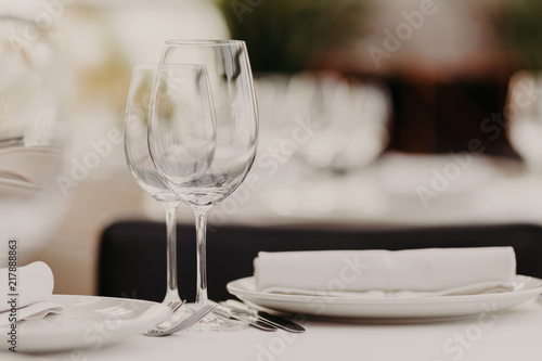 Wedding table decorated with empty wineglasses, plates and napkins in luxury cafe or restaurant. Special event celebrated in cafeteria. Rest, party food concept
