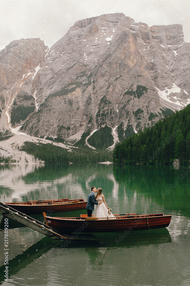 Bride and groom enjoy the moment standing in the boat somewhere in Italian Dolomites