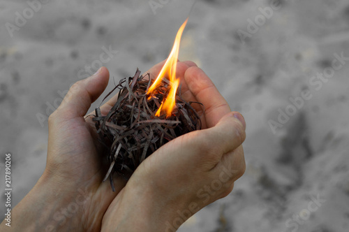 Burning wood filler in hands with matchstick, sand background photo