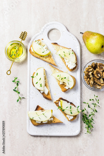 Pear and brie, honey crostini toasts on marble background. Top view, space for text.