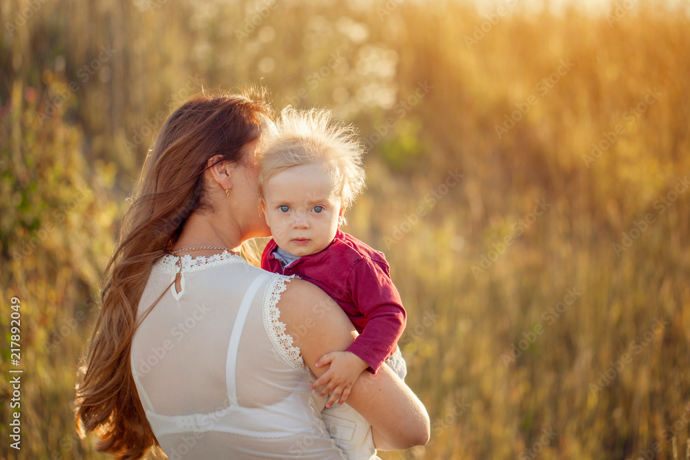 Young mother with her cute child, enjoying the sunny day over summer field. Young mother with her cute child, enjoying the sunny day over summer field.