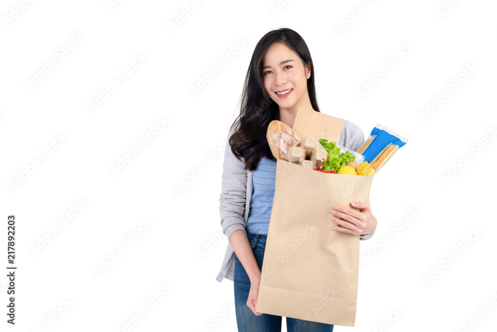 Smiling Asian woman holding paper shopping bag full of vegetables and groceries Smiling Asian woman holding paper shopping bag full of vegetables and groceries