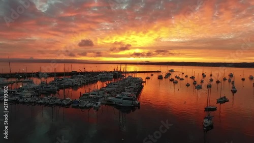 A gorgeous sunrise looking over Monterey harbor.Aerial video flying over the harbor as a boat makes it's way around the jetty wall. photo