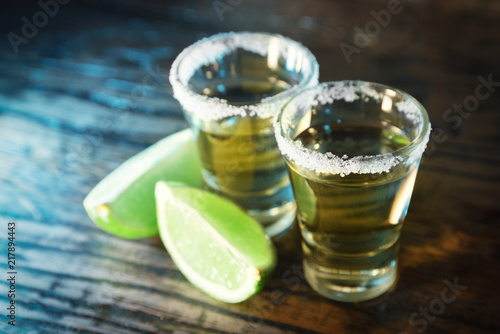 Tequila and lime in the defocus in a bar on a wooden background photo