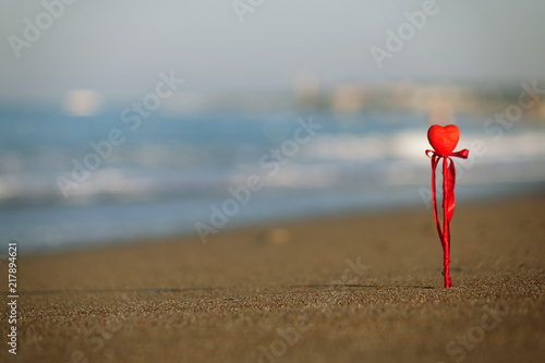 Valentine's day greeting card concept, red heart on pristine sandy beach, honeymoon vacation background. symbol of love