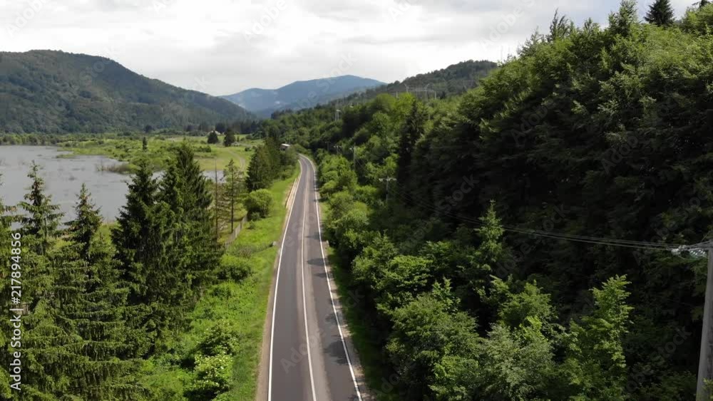 Lorry travelling on a single carriage way between the forest and the lake at noon shot with a drone in 4K, in Romania Lorry travelling on a single carriage way between the forest and the lake at noon shot with a drone in 4K, in Romania