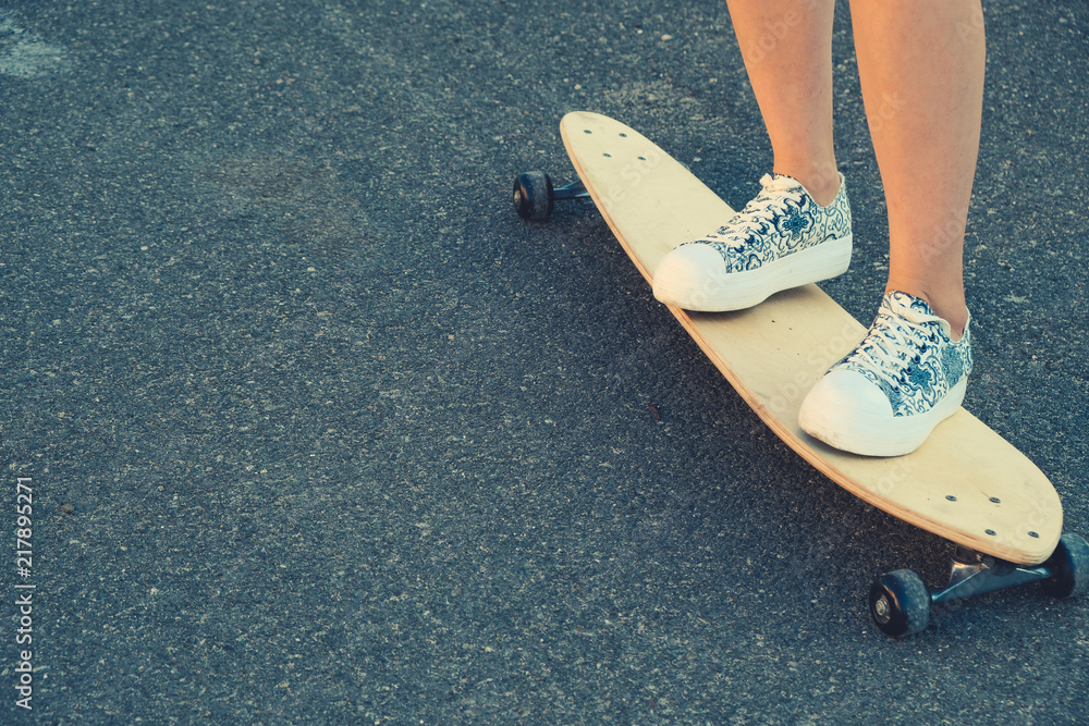 Girls legs standing on longboard closeup and a lot of copyspace Girls legs standing on longboard closeup and a lot of copyspace