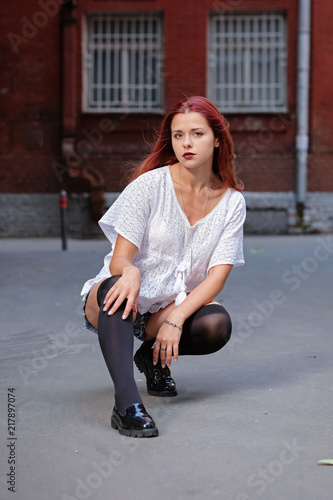 Fashion art photo. Portrait of sexy woman with long red hair, in the city.