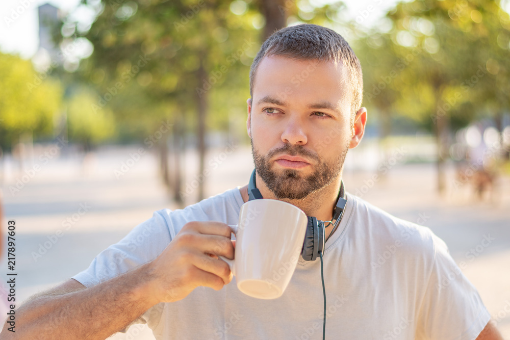 Summer in the city. A young man with a cup of coffee at sunrise. Urban background. Summer in the city. A young man with a cup of coffee at sunrise. Urban background.