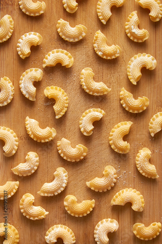 Pasta pattern on a wooden background. Roosters crest pasta shape viewed from above. Repetition concept. Top view