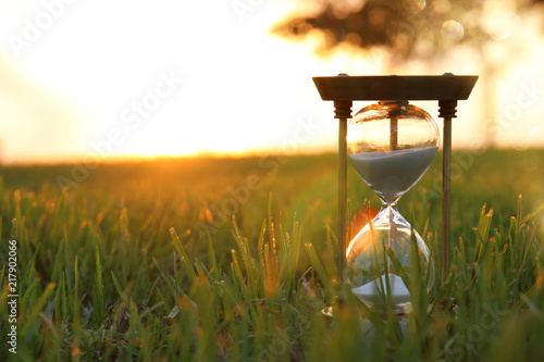 Cuadro en lienzo Hourglass in the grass time during sunset. vintage style.