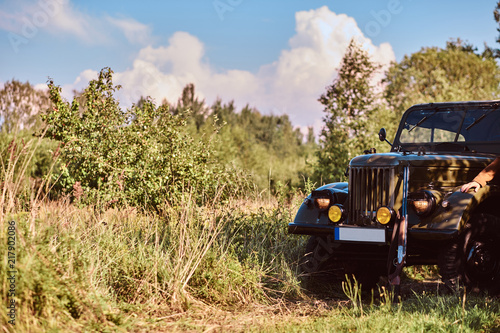 Retro military car in the steppe forest on the sunny day.