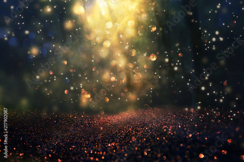 blurred abstract photo of light burst among trees and glitter golden bokeh lights.