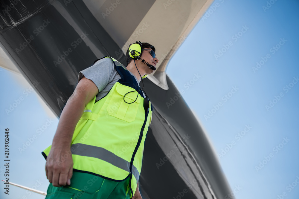 Nice view. Low angle portrait of serene man in headset. Blue sky and giant plane on background Nice view. Low angle portrait of serene man in headset. Blue sky and giant plane on background