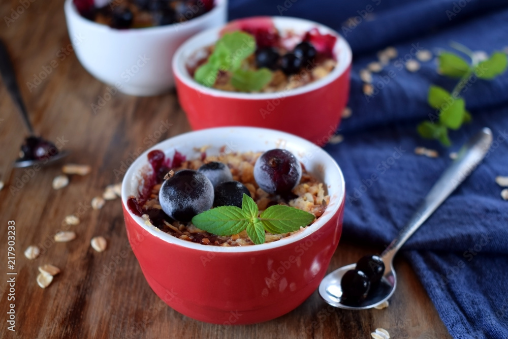 Crumble with berries in portion ceramic bowls topped with black currant and mint Crumble with berries in portion ceramic bowls topped with black currant and mint