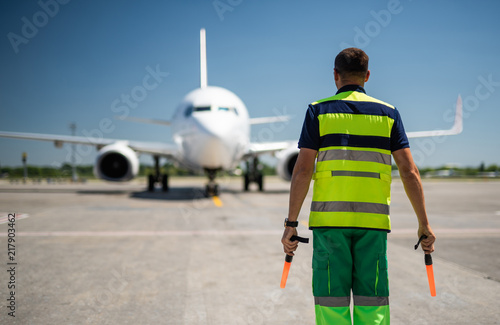 Welcome back. Back view of airport worker meeting passenger aircraft photo