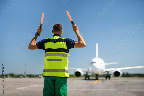 Signaling for you. Back view of aviation marshaller meeting airplane photo