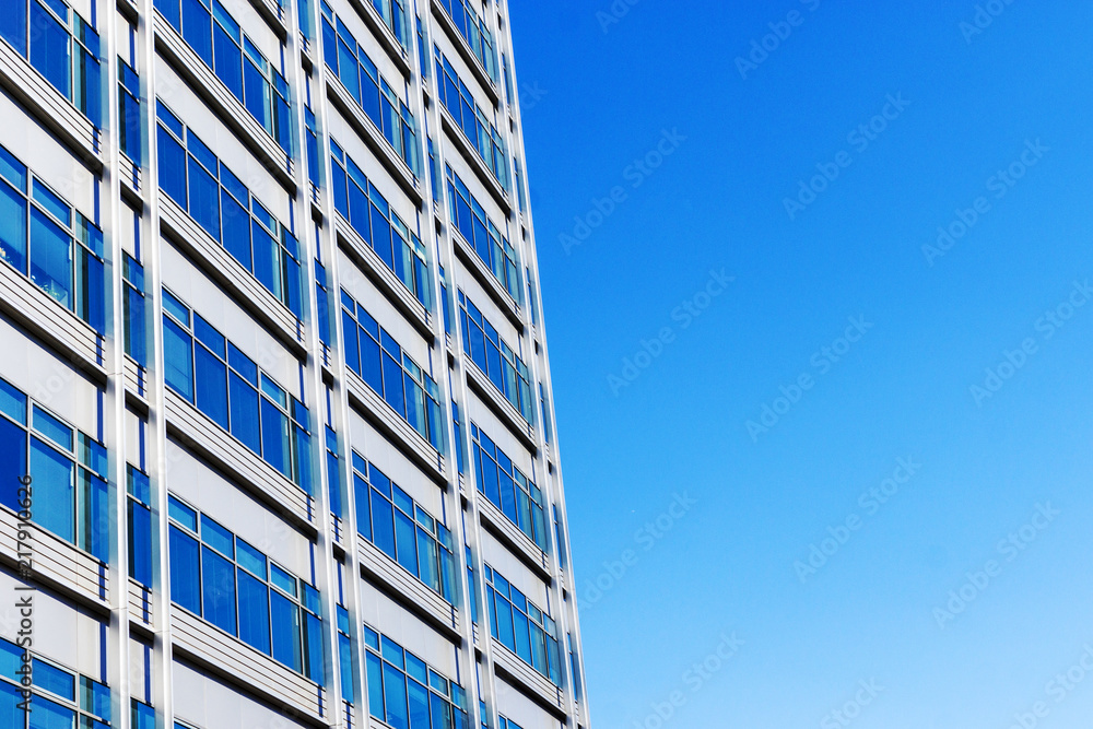 Glass facade of the building with a blue sky.