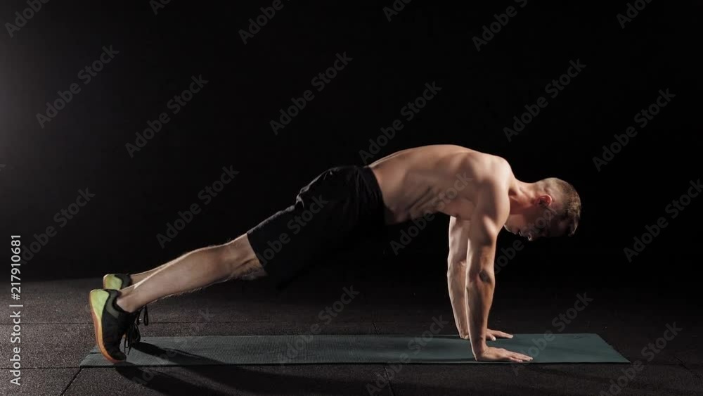 young athletic man is performing physical exercises on a sports mat in gym, working muscles of legs young athletic man is performing physical exercises on a sports mat in gym, working muscles of legs