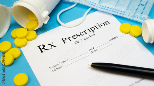 Prescription for tablet pills or drugs on blue background with bottle and yellow tablets or pills and medical mask