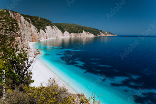 Panoramic view of Fteri beach, blue lagoon with rocky coastline, Kefalonia, Greece. Calm clear blue emerald green turquoise sea water with dark deep pattern © Igor Tichonow