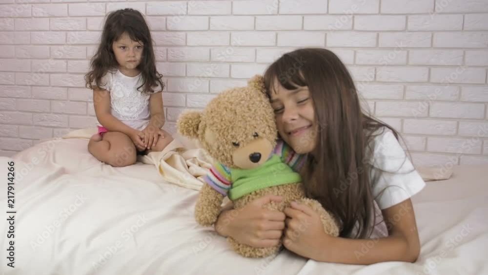 Children with a bear. Sisters in the bedroom with a bear cub. Children with a bear. Sisters in the bedroom with a bear cub.