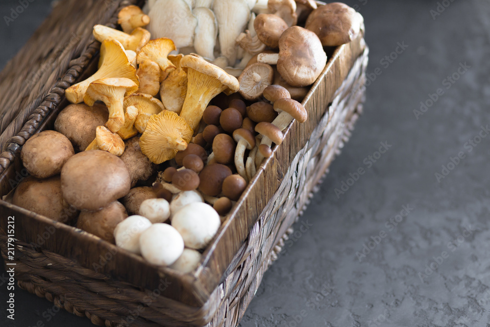 Wicker basket with forest rare delicious edible mushrooms on a dark textural background, flat lay. Wicker basket with forest rare delicious edible mushrooms on a dark textural background, flat lay.
