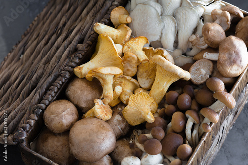 Wicker basket with forest rare delicious edible mushrooms on a dark textural background, flat lay.