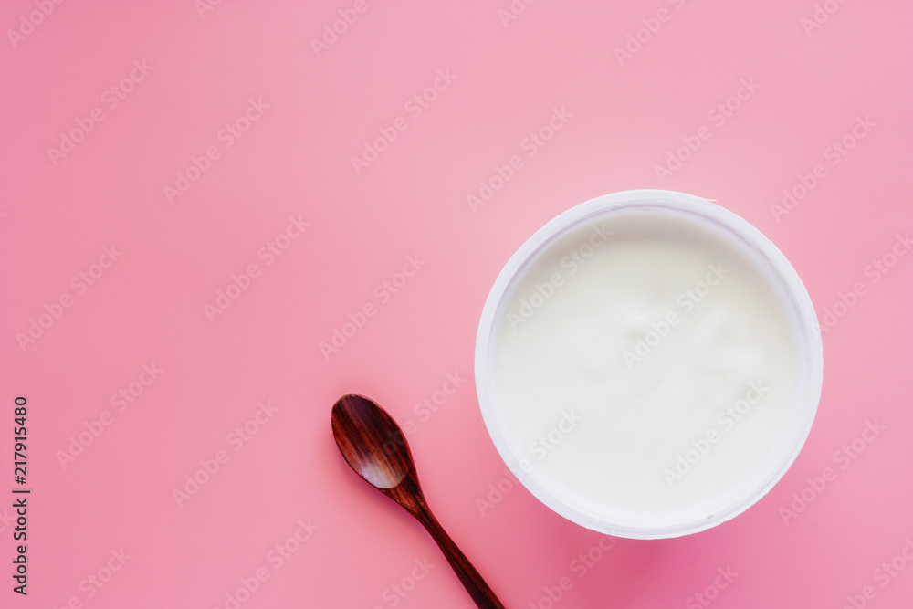 Set yogurt, natural flavour and wooden spoon on pink pastel color background for healthy eating concept Set yogurt, natural flavour and wooden spoon on pink pastel color background for healthy eating concept