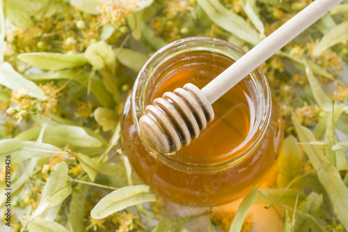 Glass jar of honey on the background of Linden blossoms.