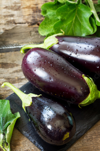Fresh healthy raw Purple Eggplant on a kitchen wooden table. The concept of Diet menu. Copy space.