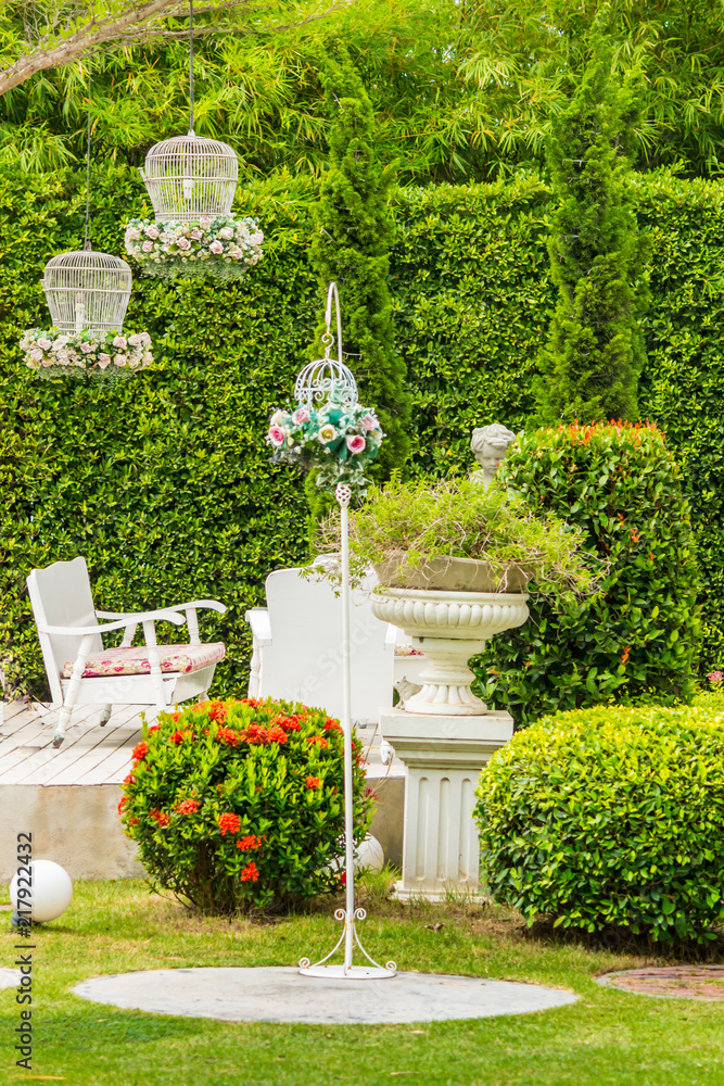 White table set and flower pot decoration on garden./ White table set with flower pot and cupid statue decoration in cozy home flower garden on summer.
