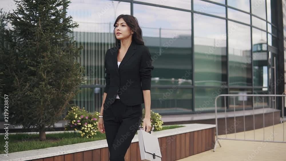 portrait of young confident business woman in suit with folder for papers in hands. a girl in a trouser suit walks down the street portrait of young confident business woman in suit with folder for papers in hands. a girl in a trouser suit walks down the street
