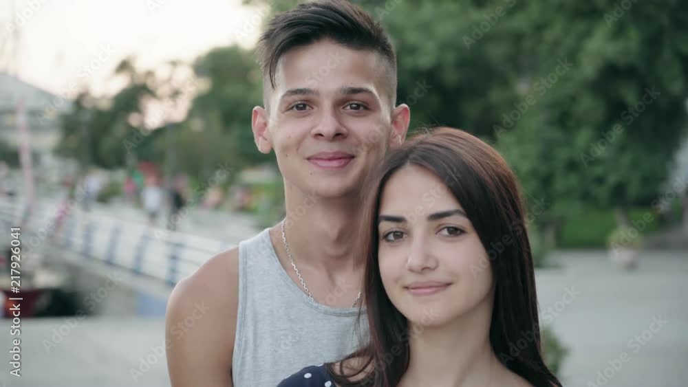 An optimistic view of a smiling and laughing young man and his stylish girl smartening up and entertaining on a river quay at splendid sunset An optimistic view of a smiling and laughing young man and his stylish girl smartening up and entertaining on a river quay at splendid sunset