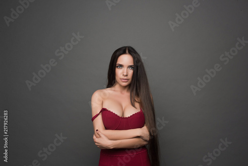 Beautiful woman with large breasts, natural make-up with beautiful long hair. Portrait of trendy, cheerful, modern, stylish, woman in eyewear isolated on grey background.