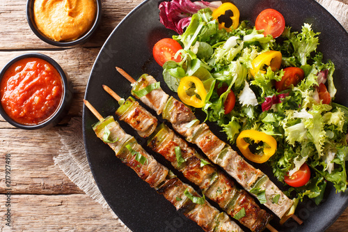 Pork shish kebab with vegetable fresh salad on a plate and sauces close-up. horizontal top view