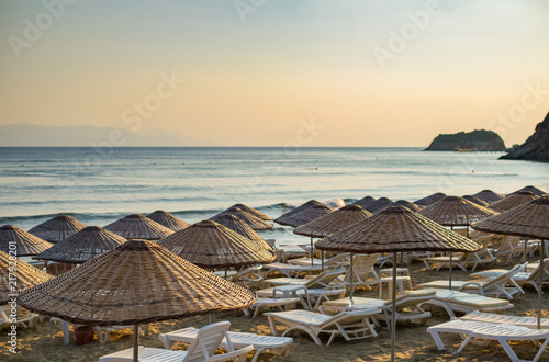 Beach umbrellas and chaise lounges with sea and evening sky in the background. photo