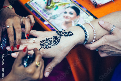 Woman mehendi artist painting henna on the woman hand photo