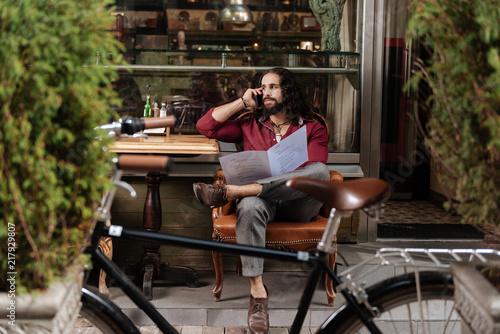 Distance connection. Handsome long haired man making a call while holding the menu in the restaurant © zinkevych