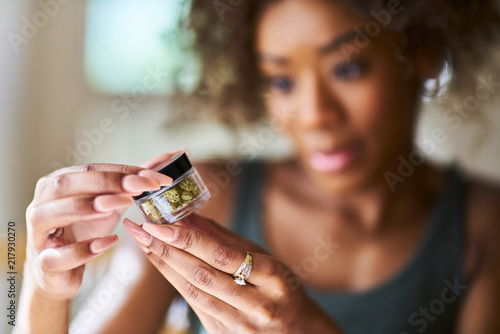 african american woman looking at bottle of marijuana close up
