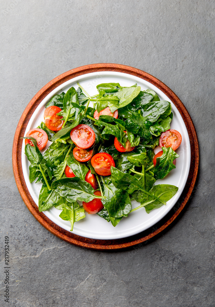 Fresh summer salad with baby spinach and tomatoes cherry. Top view, copy space. Slate gray background Fresh summer salad with baby spinach and tomatoes cherry. Top view, copy space. Slate gray background