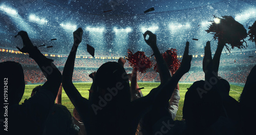Fans celebrating the success of their favorite sports team on the stands of the professional stadium while it's snowing