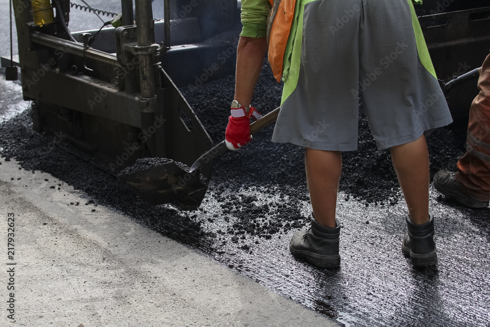 Workers on a road construction, industry and teamwork. builders workers at asphalting paver machine during Road street repairing works Workers on a road construction, industry and teamwork. builders workers at asphalting paver machine during Road street repairing works